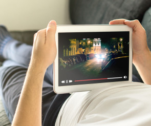 Mann liegt auf dem Sofa und schaut Film auf Tablet 