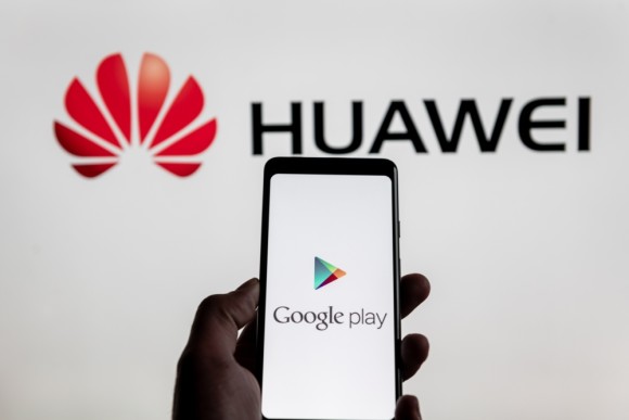 Huawei-Logo mit Android-Smartphone im Vordergrund 