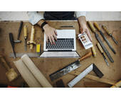 Handwerker mit Laptop auf der Werkbank