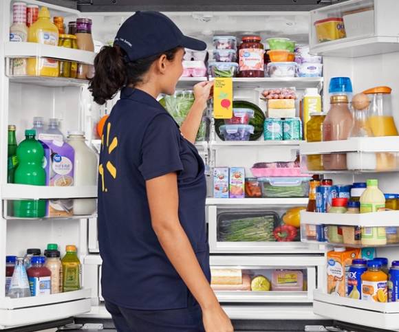 Frau steht vor einem vollen Kühlschrank 