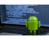 Android-Figur mit Code auf Comoputer-Bildschrim im Hintergrund