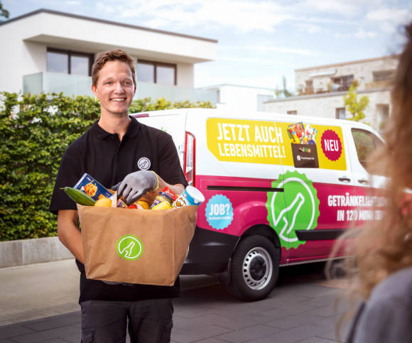 Mann trägt Lebensmittel von Auto zu Haus der Kundin 