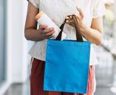 Frau steckt Plastikflasche in Einkaufstasche