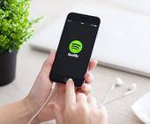 Zwei Hände halten ein Smartphone, das ein Spotify-Logo zeigt