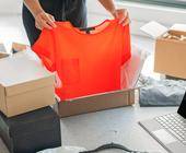 Frau packt T-Shirt aus Online-Lieferung aus