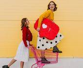 Mädchen posieren mit Herzsymbol und Einkauswagen
