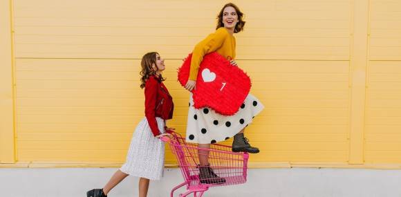 Mädchen posieren mit Herzsymbol und Einkauswagen 