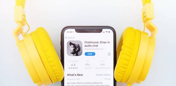 Clubhouse-App auf Smartphone mit gelben Kopfhörern 