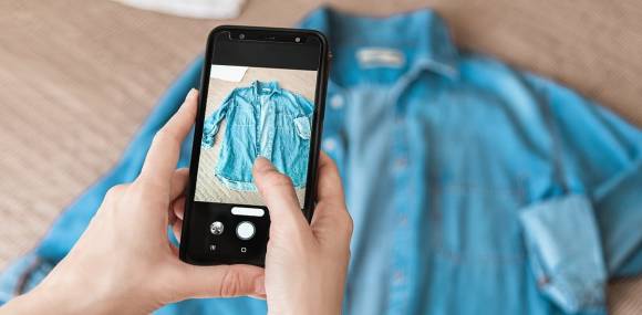 Person fotografiert Denim-Shirt auf Smartphone  