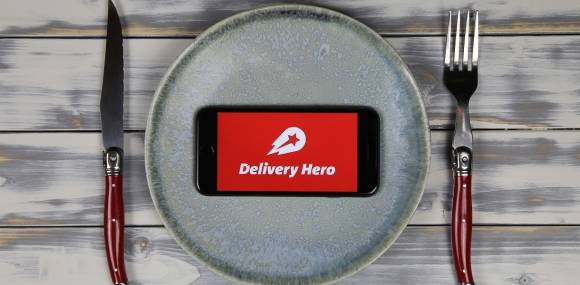Delivery Hero App auf Smartphone auf Teller  