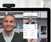 Monitor mit montierter Logitech-Webcam, auf dem Bildschirm das Portrait eines Mannes