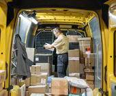 Ein Post-Angestellter in einem Post-Lieferwagen, umgeben von Paketen