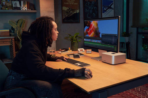 Das Foto zeigt ein junge Person vor einem Apple Studio Display, das mit einem Mac Studio verbunden ist 