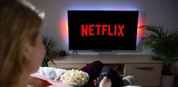 Frau vor dem Fernseher mit Netflix-Logo 