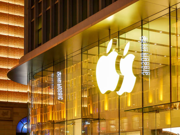 Leuchtendes Apple-Logo an einer gläsernen Gebäudefassade 