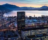 Gebäude in Zug, Dämmerungslicht, im Hintergrund sind der Zugersee und die Alpen