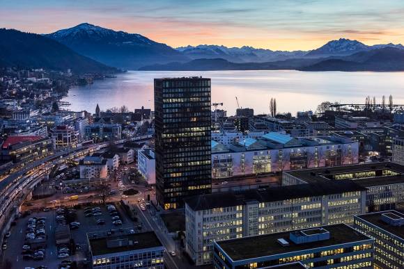 Gebäude in Zug, Dämmerungslicht, im Hintergrund sind der Zugersee und die Alpen 