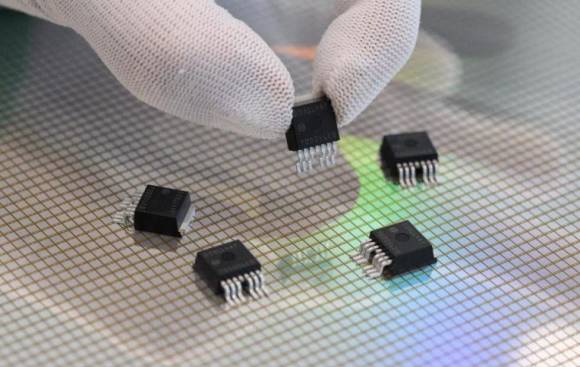 Mitarbeiterin präsentiert in der Halbleiterfabrik von Bosch in Dresden mikromechanische Sensoren über einem 300-Millimeter-Wafer 