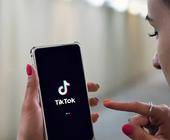 junge Frau mit Handy und TikTok-App