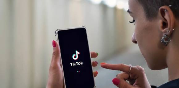 junge Frau mit Handy und TikTok-App 