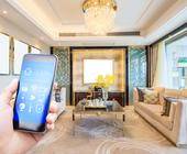 Smartphone zeigt Smart-Home-Icons, in der Hand einer Person, die in einer schicken Wohnung steht