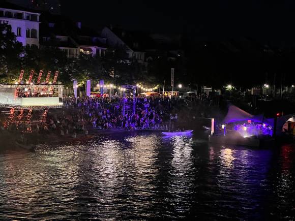 Besucherkulisse einer nächtlichen Konzertveranstaltung an einem Fluss