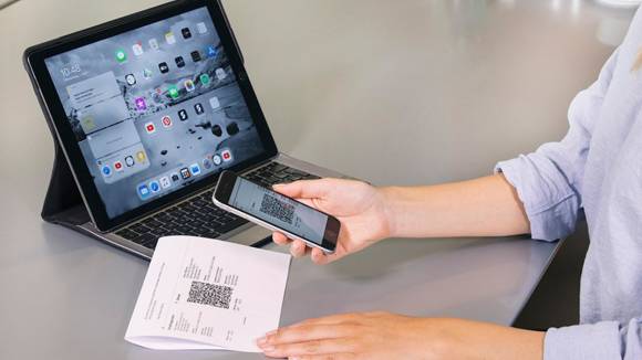 Person hält ein Smartphone über eine Schweizer QR-Rechnung Person hält ein Smartphone über eine Schweizer QR-Rechnung