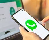 Smartphone in der Hand einer Person zeigt das WhatsApp-Logo