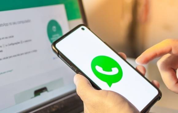 Smartphone in der Hand einer Person zeigt das WhatsApp-Logo 