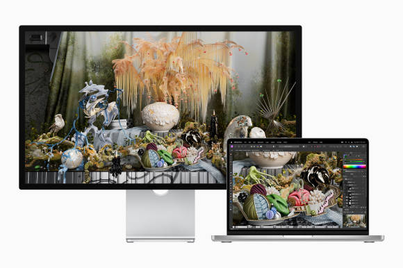Das Studio Display bildet die perfekte Ergänzung zu einem MacBook – auf diesem Bild zu einem MacBook Pro Ein geöffnetes MacBook Pro steht neben einem Studio Display