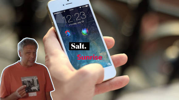 Videostandbild zeigt Redaktor Daniel Bader und im Hintergrund eine Hand mit einem Smartphone 