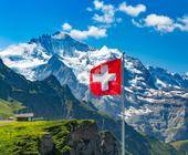 Symbolbild zeigt Schweizer Fahne. Im Hintergrund die Alpen.