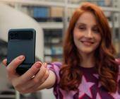 Eine Frau hält das halb zugeklappte Motorola Razr 40 für ein Selfie vor sich