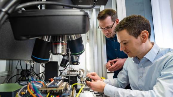 Zwei Mitarbeiter des Fraunhofer AISEC prüfen elektronische Bauteile mit Spezialgeräten auf Herz und Nieren 