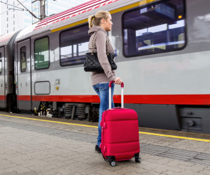 Frau vor Zug mit Koffer 