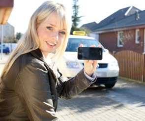 Frau mit Smartphone vor Taxi 