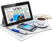 Kugelschreiber, iPad, Smartphone und Kaffee stehen auf Zeitung