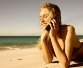 Junge Frau am Strand beim Telefonieren