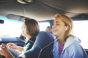 Zwei Frau sitzen in einem Auto und hören über Kopfhörer Musik