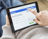 Person surft auf Facebook mit Tablet