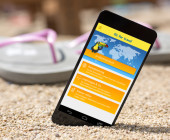 Smartphone mit Reise-App am Strand