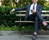 Mann sitzt mit Handy auf Bank
