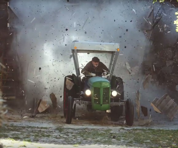 Mann fährt mit Traktor durch Scheunentor 