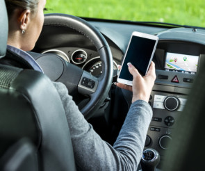 Frau hält im Auto ihr Smartphone in der Hand 