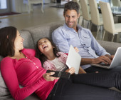 Familie sitzt auf der Couch mit mobilen Geräten