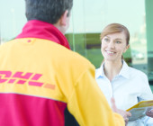 DHL-Bote übergibt Fau Paket an der Haustür