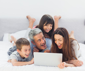 Eltern mit zwei Kindern und Computer im Bett 