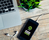 Smartphone mit Spotify-App neben Laptop