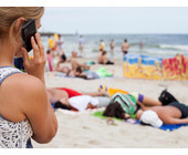 Frau am Strand mit Smartphone