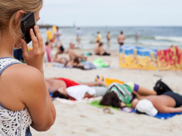 Frau am Strand mit Smartphone 